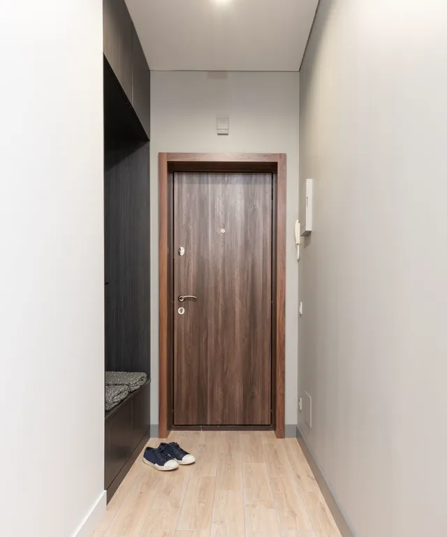Recibidor con puerta de madera, armario empotrado y suelo claro