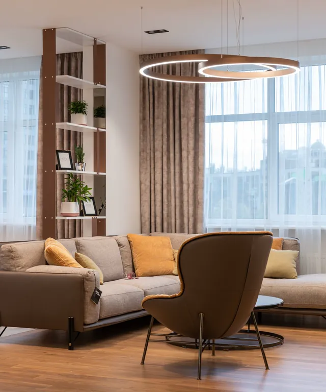 Salón moderno con sofá, sillón y una gran ventana con cortina